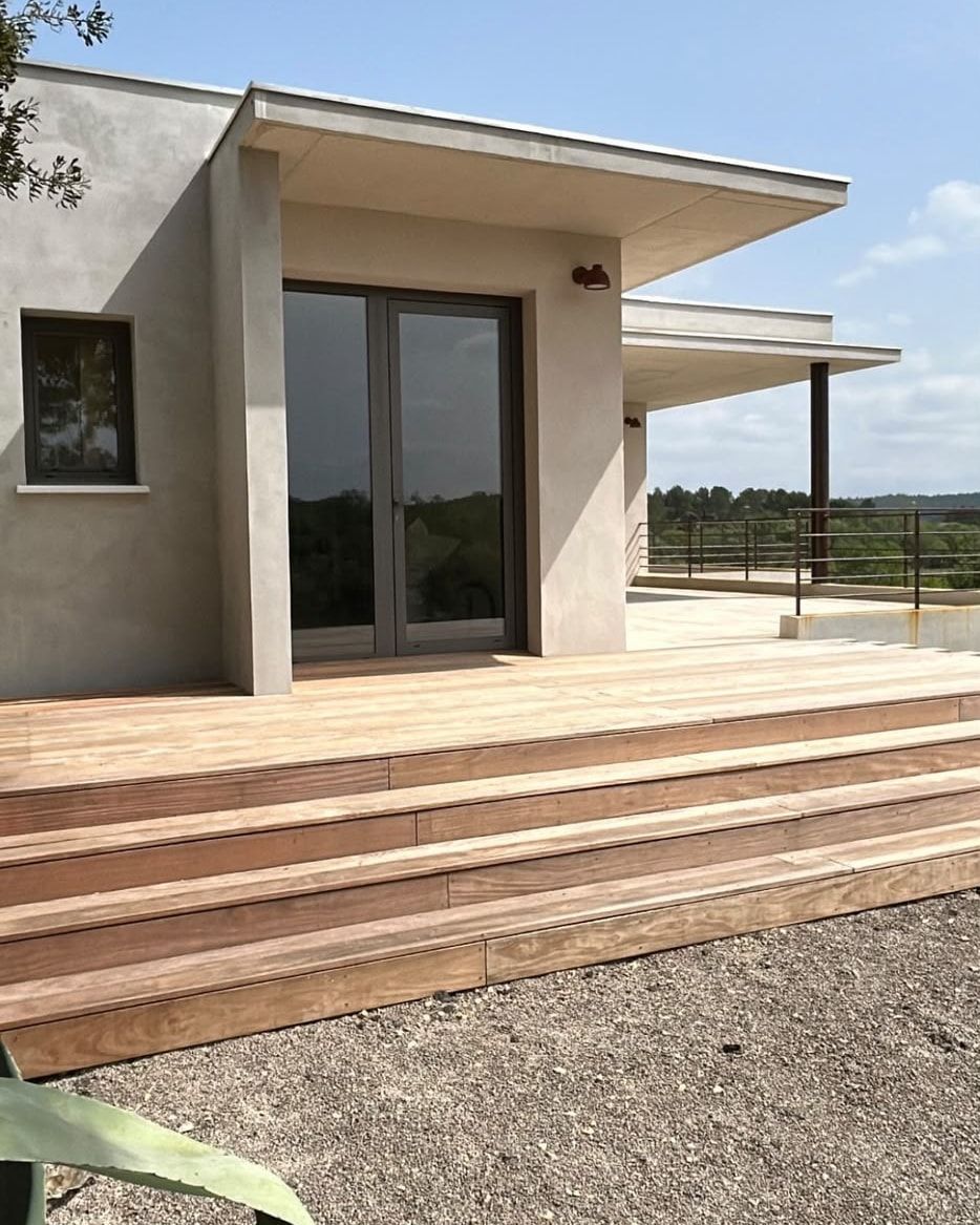 Terrasse en bois exotique et emmarchement de trois marches devant l’entrée vitrée d’une villa à toit plat, à Combaillaux