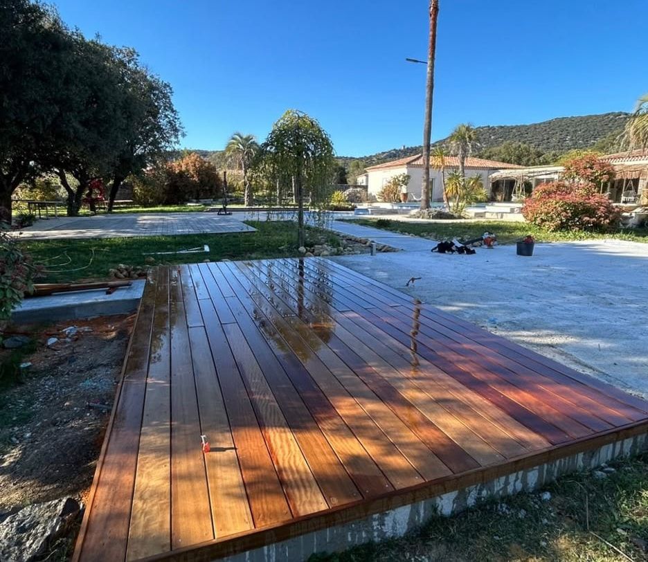 Terrasse en ipé huilé encastrée dans le dallage près du bassin, palmier et maison aux tuiles