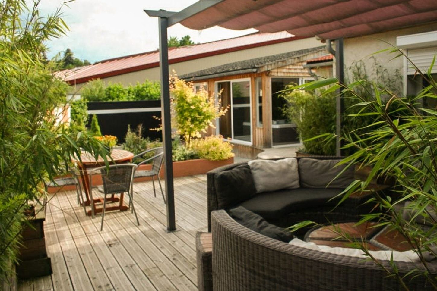 Terrasse bois sous pergola avec salon de jardin et bambous en pots